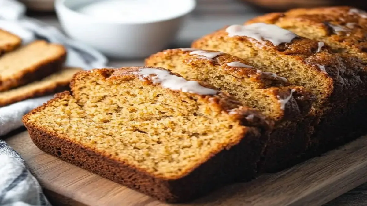 A loaf of Amish Friendship Bread on a wooden board surrounded by ingredients like flour and sugar, symbolizing the tradition of sharing the starter